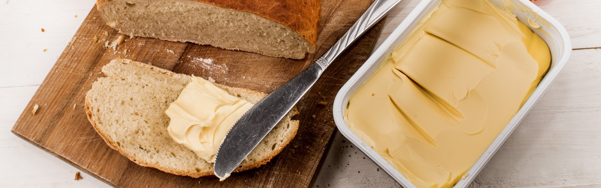 507046423 domaci peceni kruh s margarinom i nozem na dasci za rezanje