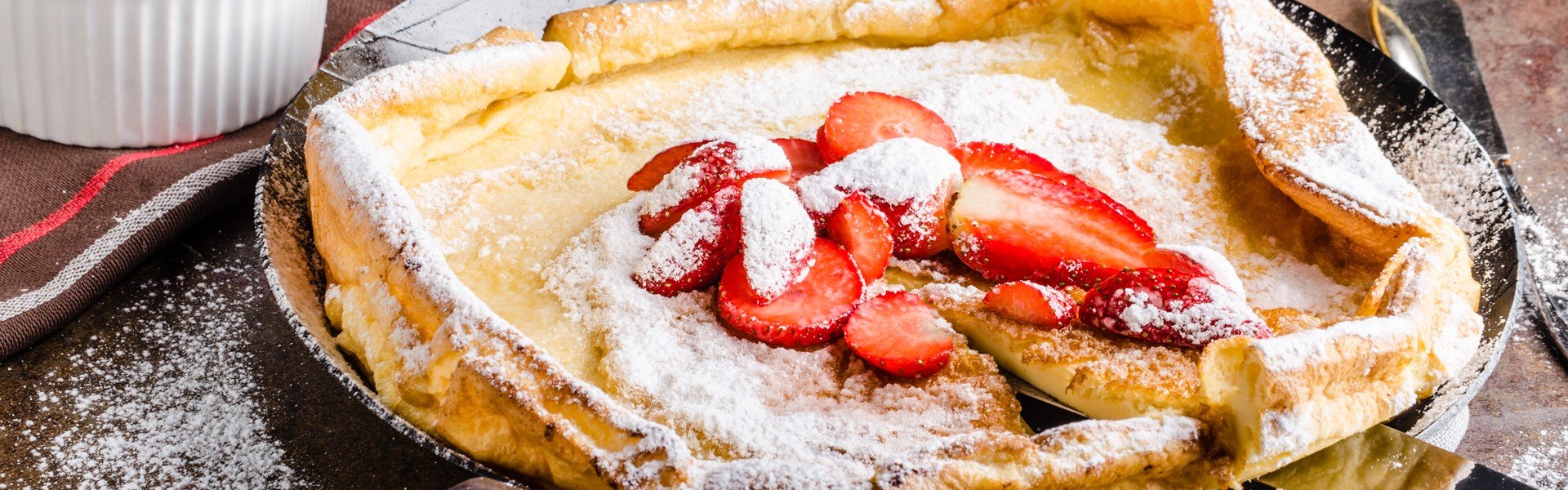 416806747 Dutch Baby palacinka na tanjuru s jagodama i ecerom u prahu