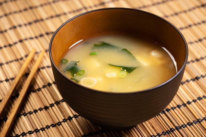 Miso soup with tofu and seaweed in brown Japanese bowl