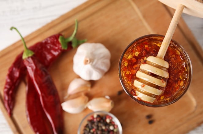2038108130 Board with hot honey and ingredients on table