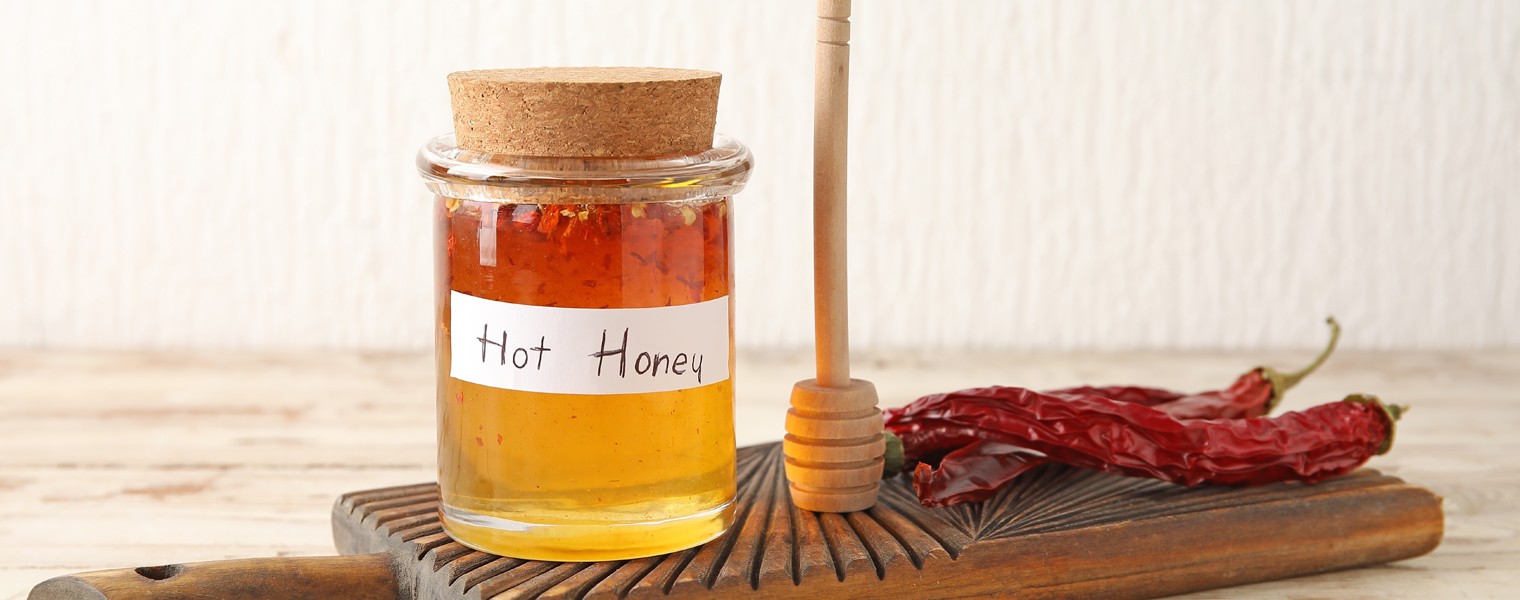 Jar of hot honey and dry chili peppers on wooden table
