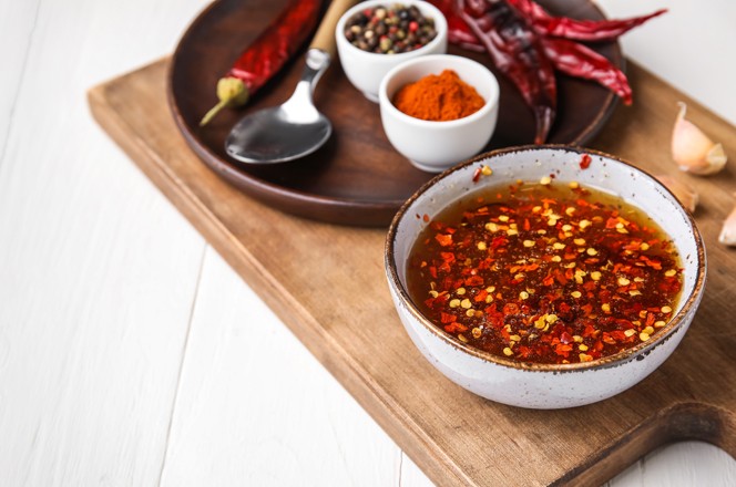 2186190255 Bowl of hot honey sauce on white wooden background with space for text