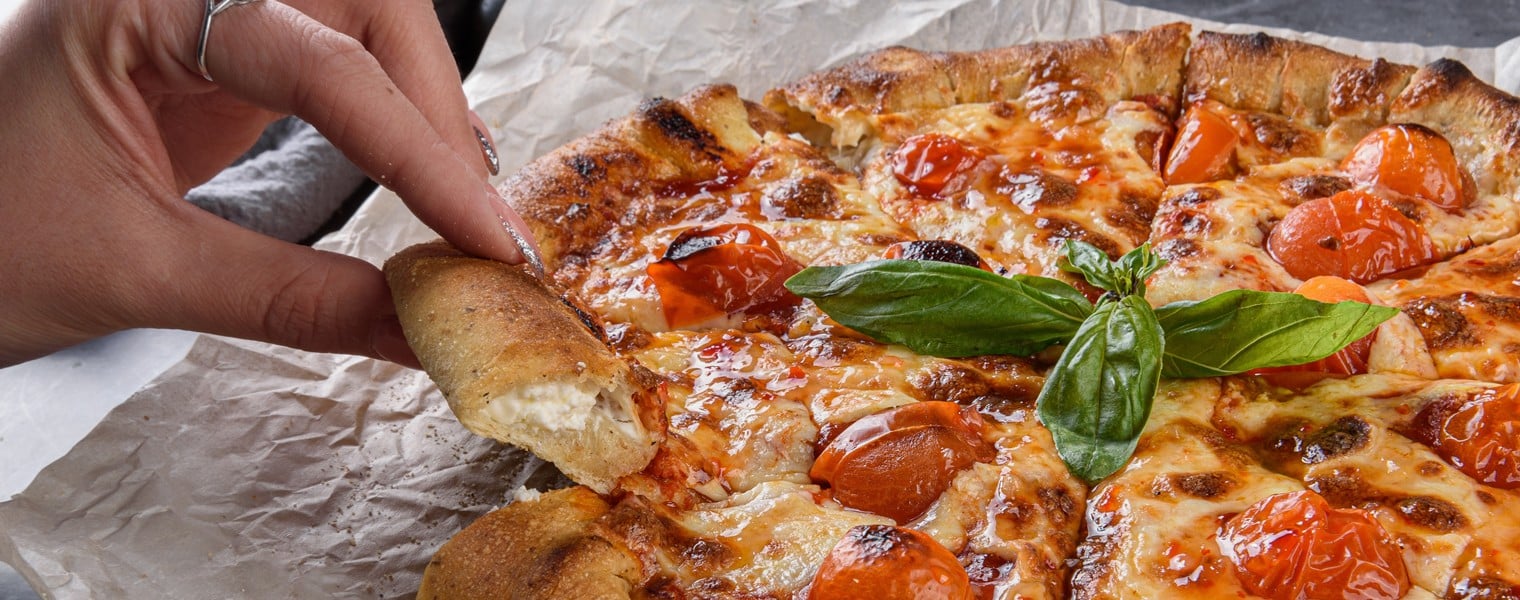 2248715671 Hot pizza Margaritas on a gray concrete countertop. A hand takes slices of delicious pizza. Cheese in a pizza crust. Tasty vegetable pizza.