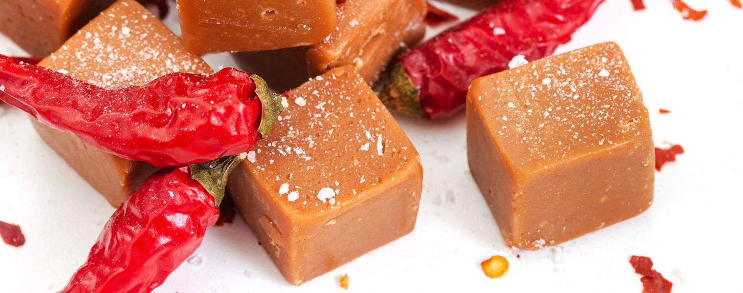 caramel fudge with chili flakes and whole chilis, sweet and spicy treats on white