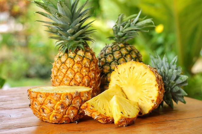 1503954347 Narezani i prepolovljeni ananas (Ananas comosus) na drvenom stolu.