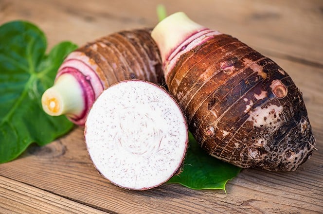 2055084893 Korijen tara s polovinom kri ke na listu tara, na drvenoj podlozi. Svje i sirovi organski taro korijen spreman za kuhanje.