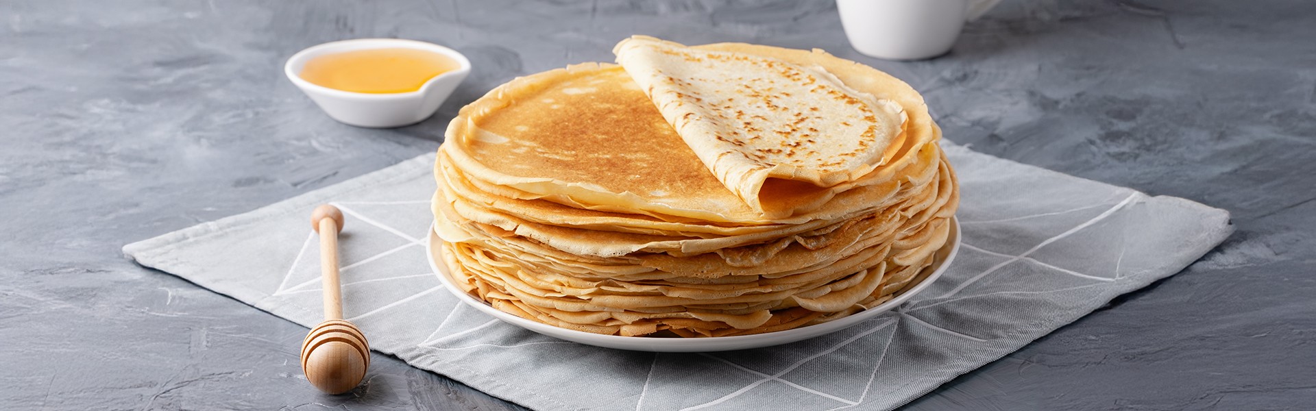 2426361095 Hrpa tradicionalnih ruskih palacinki blini na sivoj podlozi s prostorom za tekst. Domace ruske tanke palacinke blini.