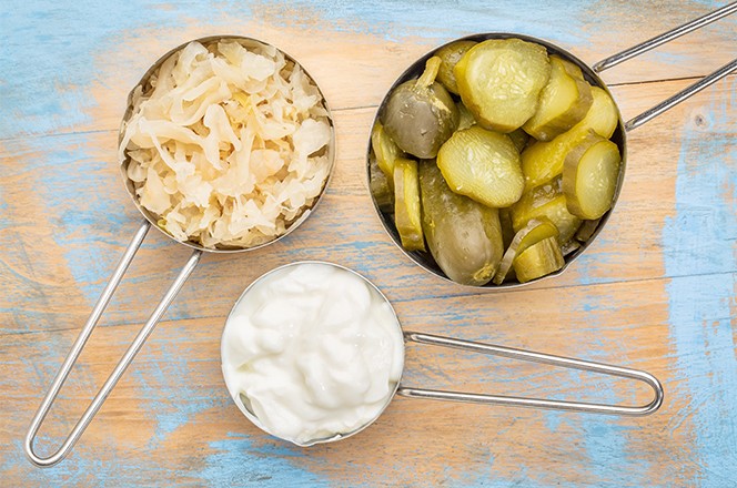 344352596 Kiseli kupus, kiseli krastavci i jogurt popularna probioticka fermentirana hrana u tri mjerne posude na rustikalnoj drvenoj podlozi.