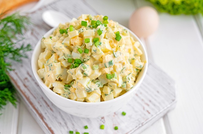 2085935359 Salata od jaja s nasjeckanim mladim lukom na vrhu, poslu ena u bijeloj zdjeli idealna za pripremu sendvica, na bijeloj drvenoj podlozi.
