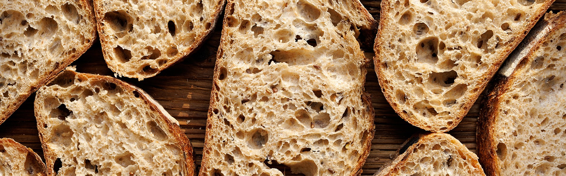 Sourdough bread slices on wooden background, top view. Bread background