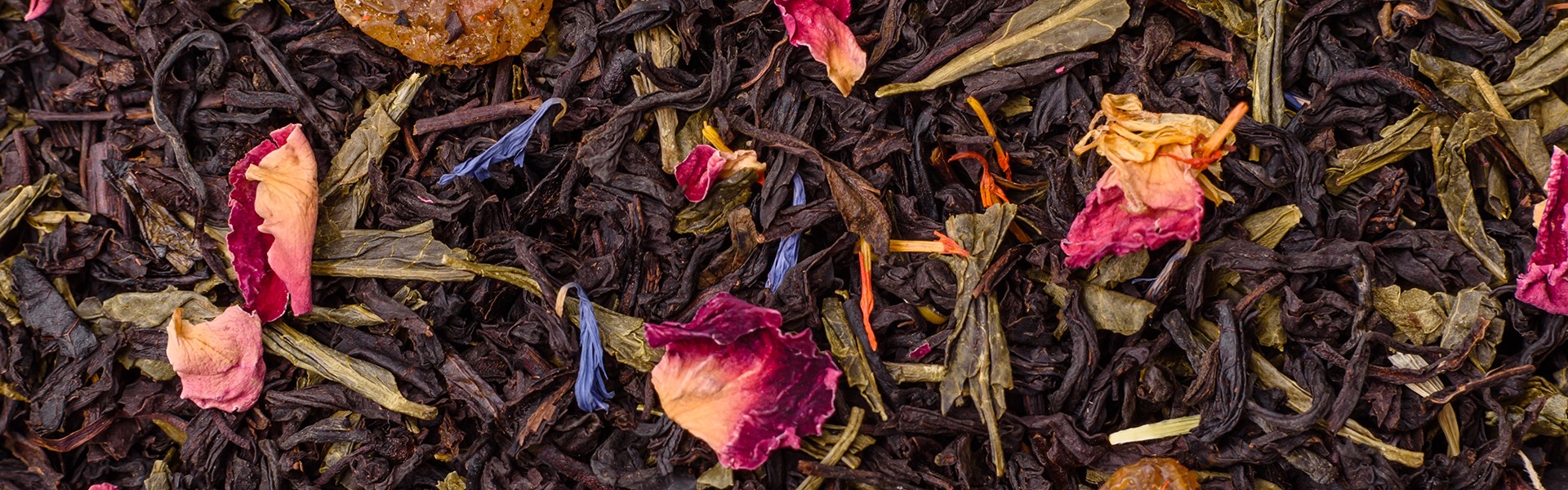 Dry tea mix blend black, green and flower petals in bowl on dark concrete background