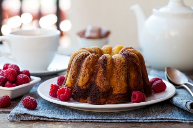 Chocolate marble bundt cake with a cup of tea on wooden table. Close up. Copy space.