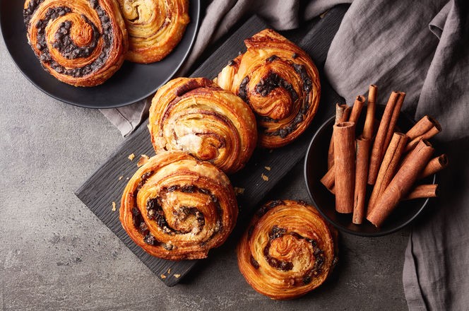 Freshly baked sweet buns on black board on grey stone background, top view