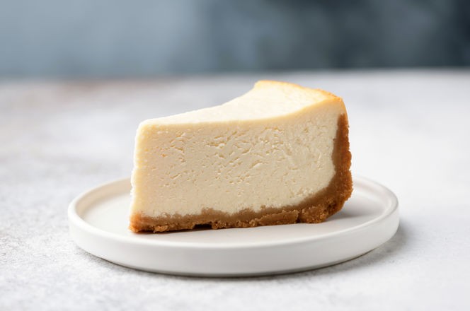 Slice Of Classical New York Cheesecake On White Plate. Closeup View