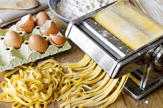 Fresh pasta cutting in machine. Fettuccini homemade.