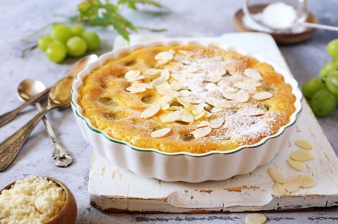 French cuisine. Green grape clafoutis from almond flour, almonde petals dressing on light background