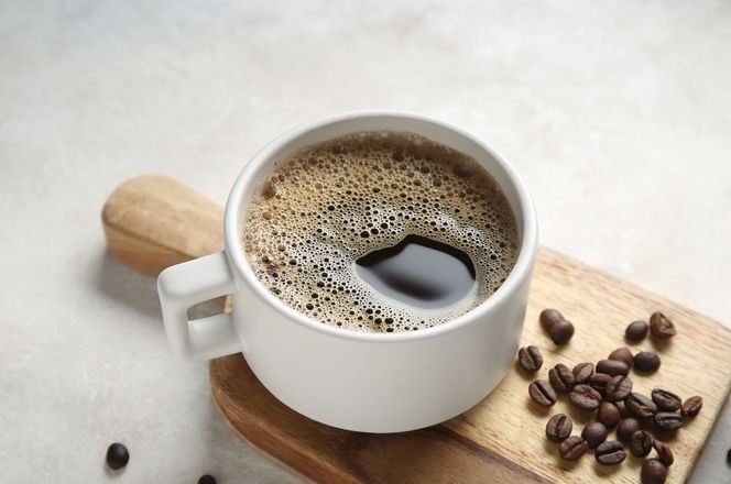 Cup of hot coffee and beans on white background
