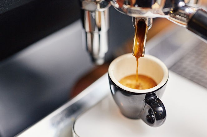 Professional espresso machine pouring strong looking fresh coffee into a neat ceramic cup