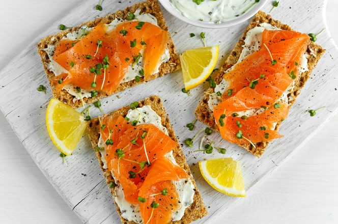 Homemade Crispbread toast with Smoked Salmon, Melted Cheese and cress salad. on white wooden board.