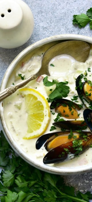 Chowder - delicious fish soup with mussels in a bowl on light grey slate, stone or concrete background. Top view with copy space.
